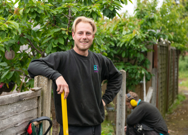 Men working in garden repairing fence