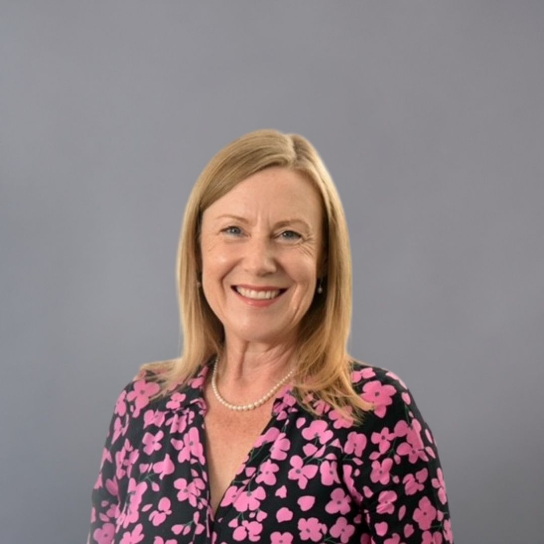 A smiling woman wearing a black shirt with a pink flower pattern