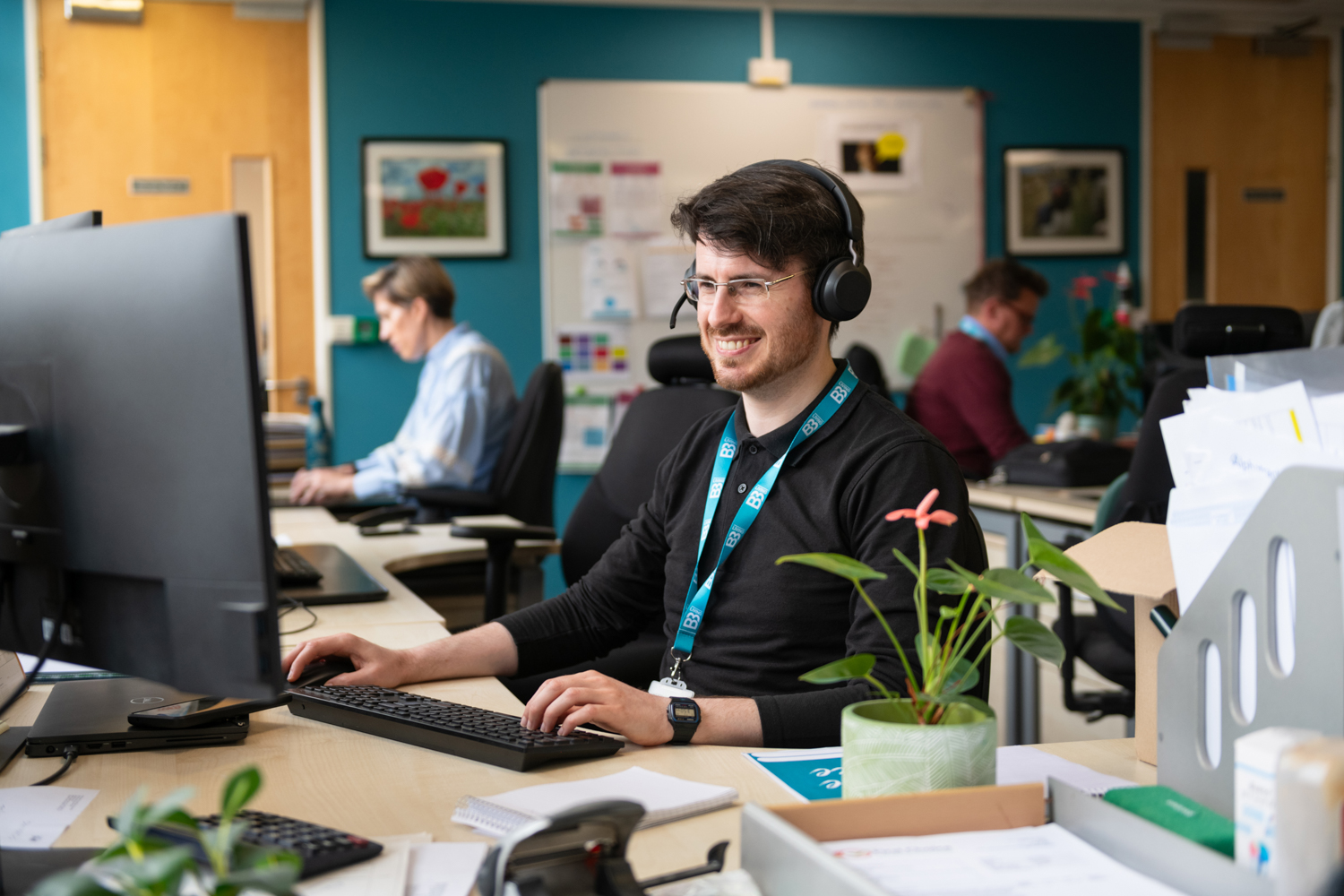 Man wearing a headset smiling at computer screen